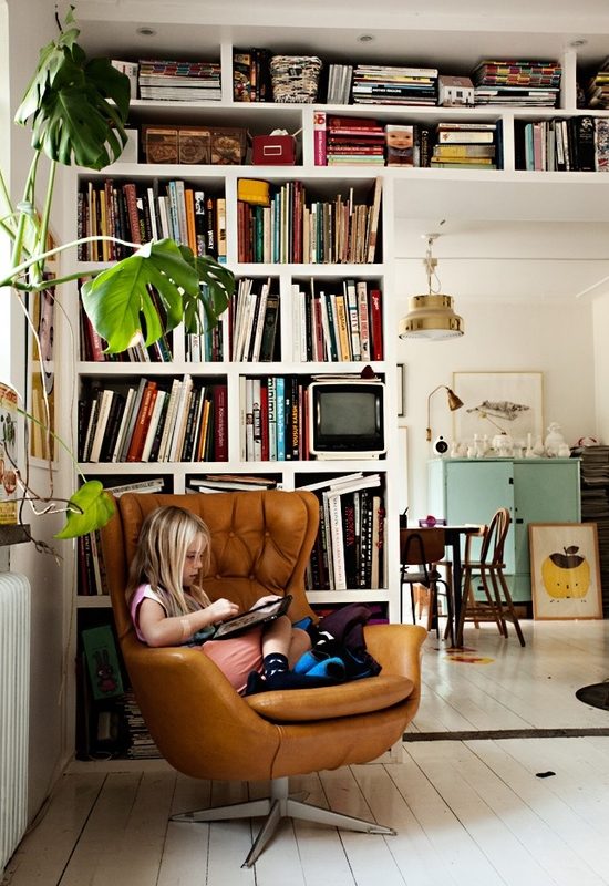 Child reading on chair, surrounded by bookshelves