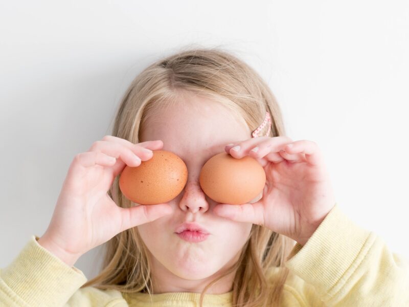 Child covering her eyes with two eggs