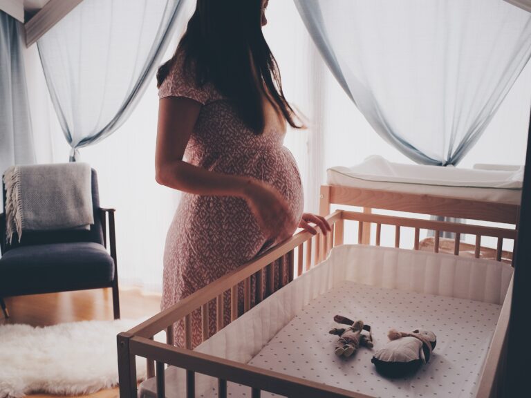 Pregnant mum stood by cot