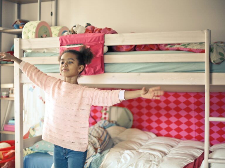 Girl with arms stretched beside her bunkbed