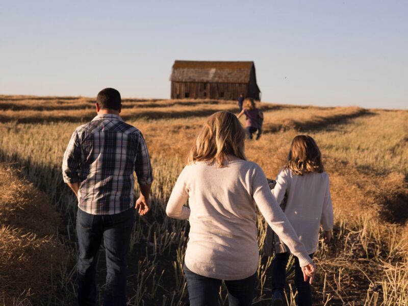 Family walking through a field towards a barn